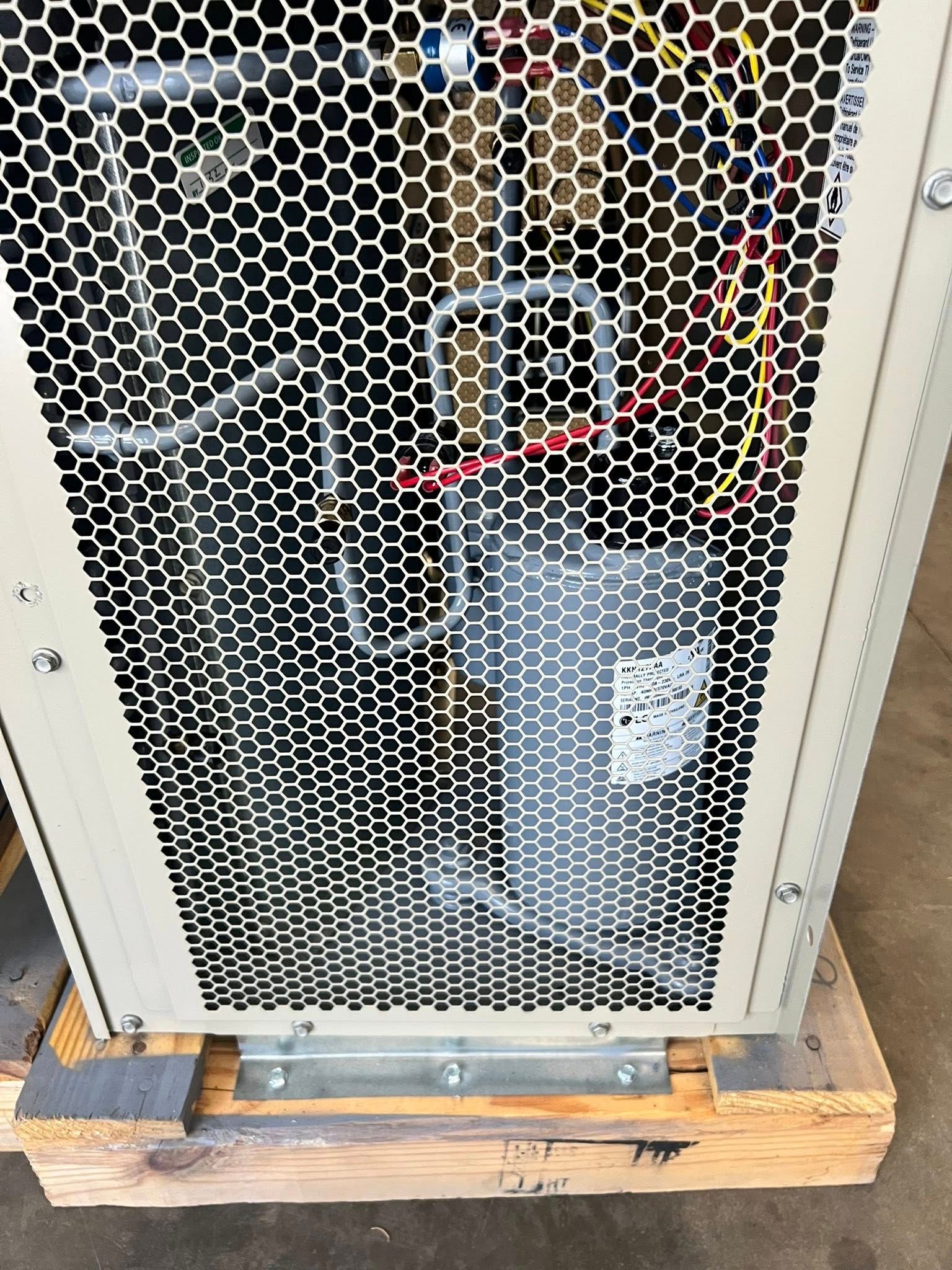 The interior of an industrial HVAC compressor unit with exposed metal pipes and wiring behind a protective wire mesh.