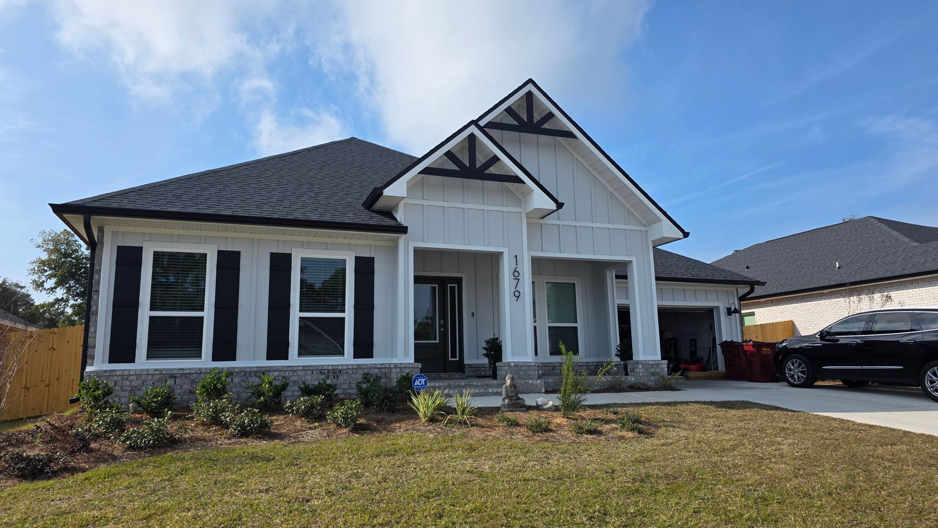 Light blue house with black shutters, dark roof, small front yard, and overcast sky.