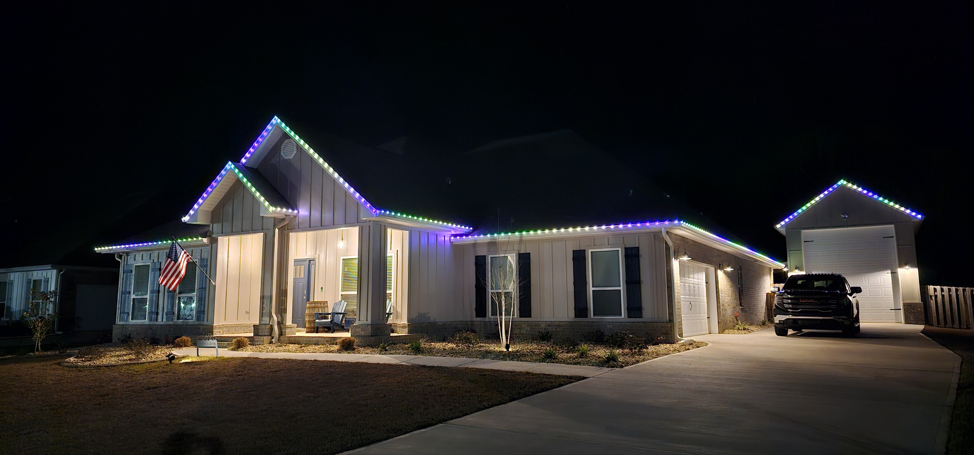 House decorated with colorful Christmas lights at night, a car is parked in the driveway.