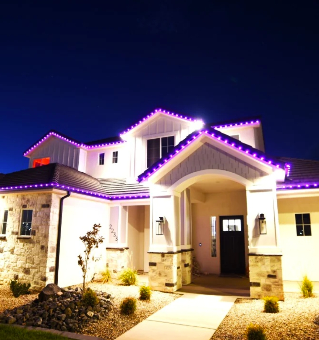 House with colorful LED lights on the roof, porch, and garage, at night.