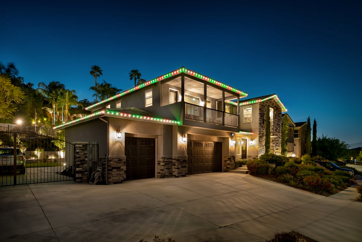 House exterior at night, lit with purple lights along the roofline.