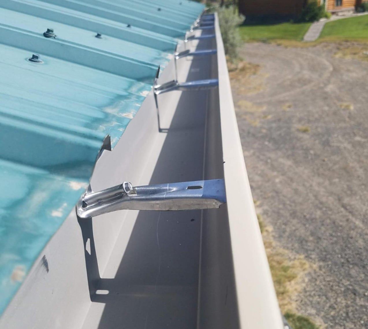 Close-up view of a metal rain gutter attached to a blue roof.