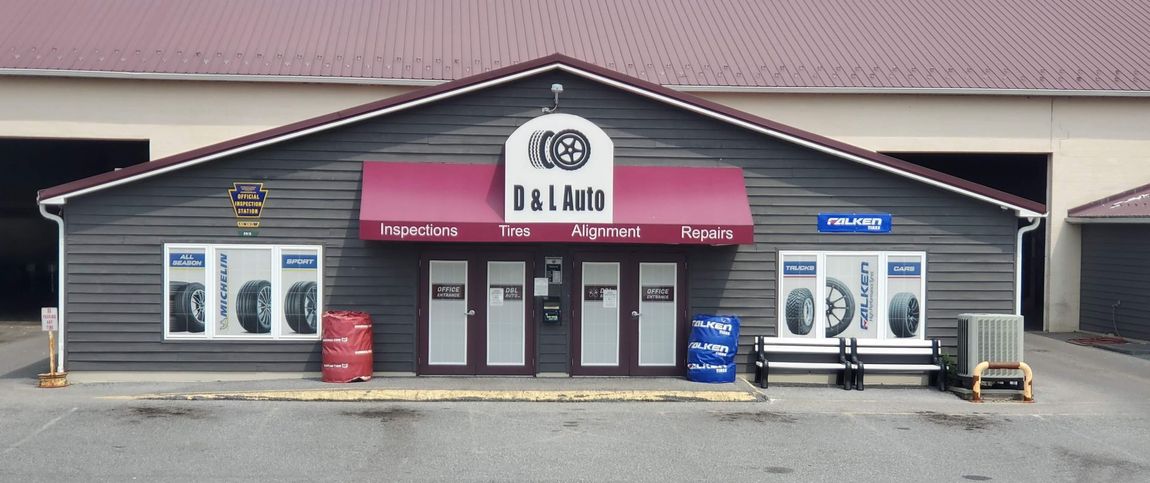Exterior view of an auto repair shop with a burgundy awning, signs, and tire displays.