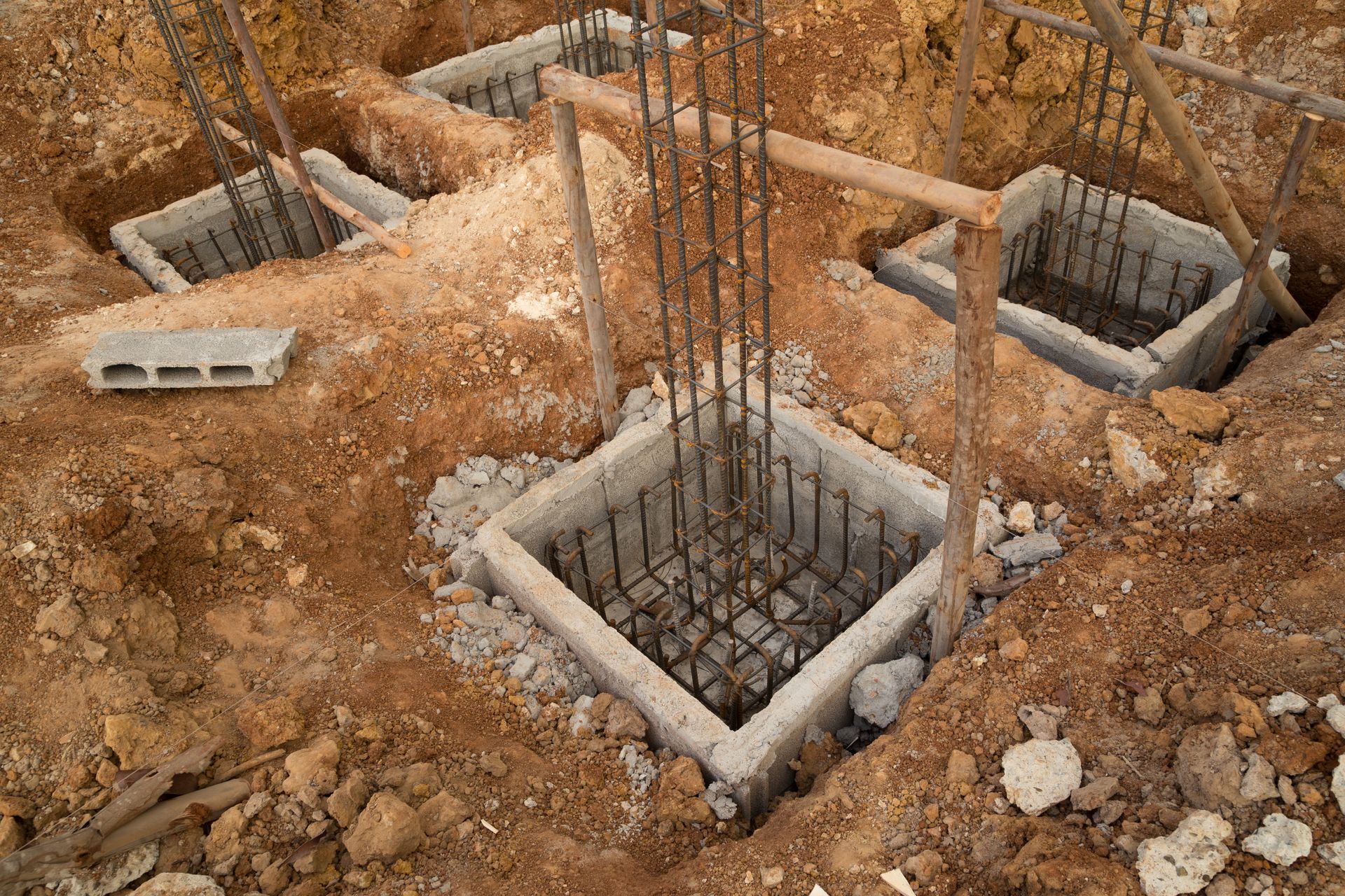 A construction site with concrete blocks and steel bars in the dirt.