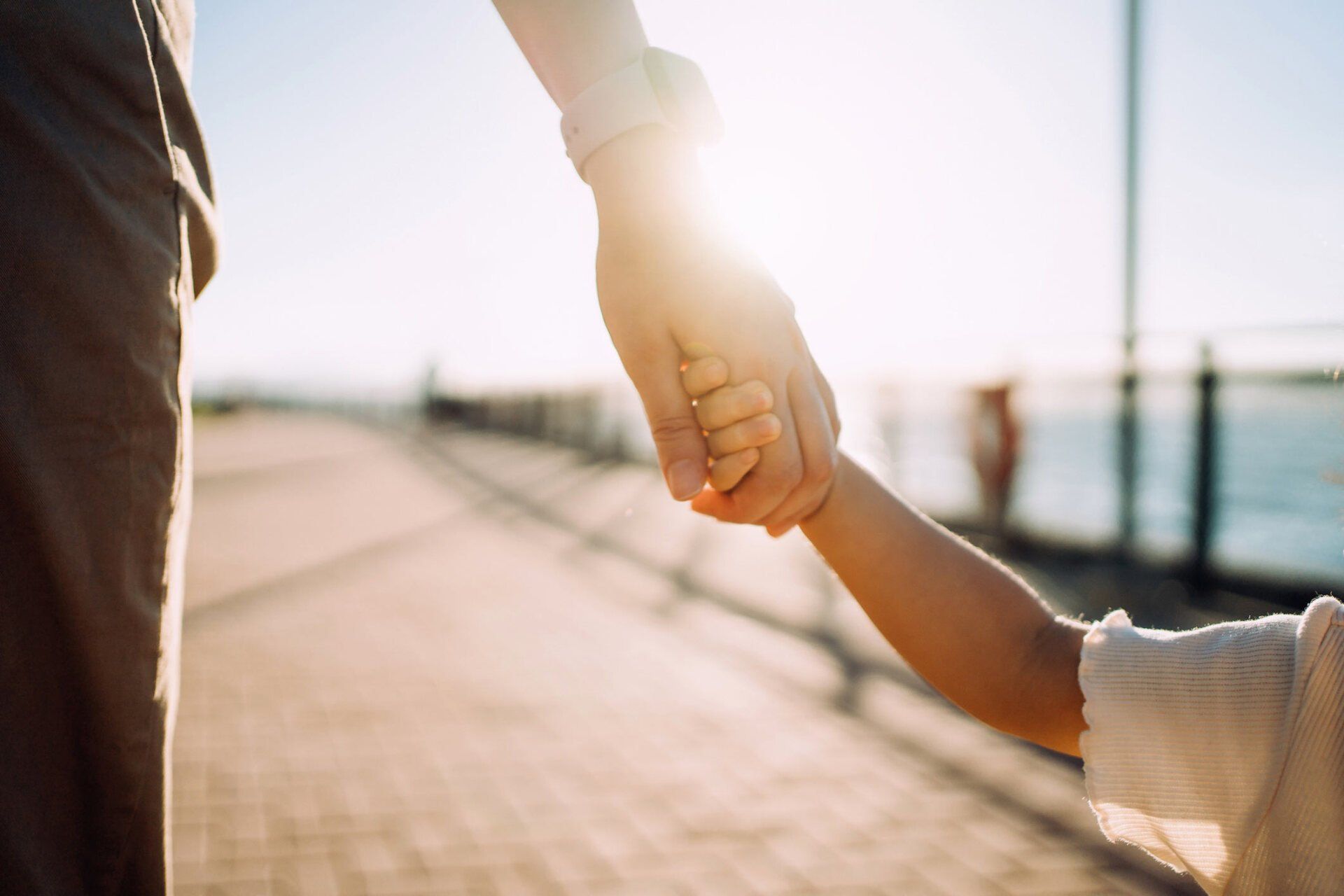 Parent holding child's hand on sunny day — Jacksonville, FL — Beaches Family Law Parent holding child's hand on sunny day — Jacksonville, FL — Beaches Family Law
