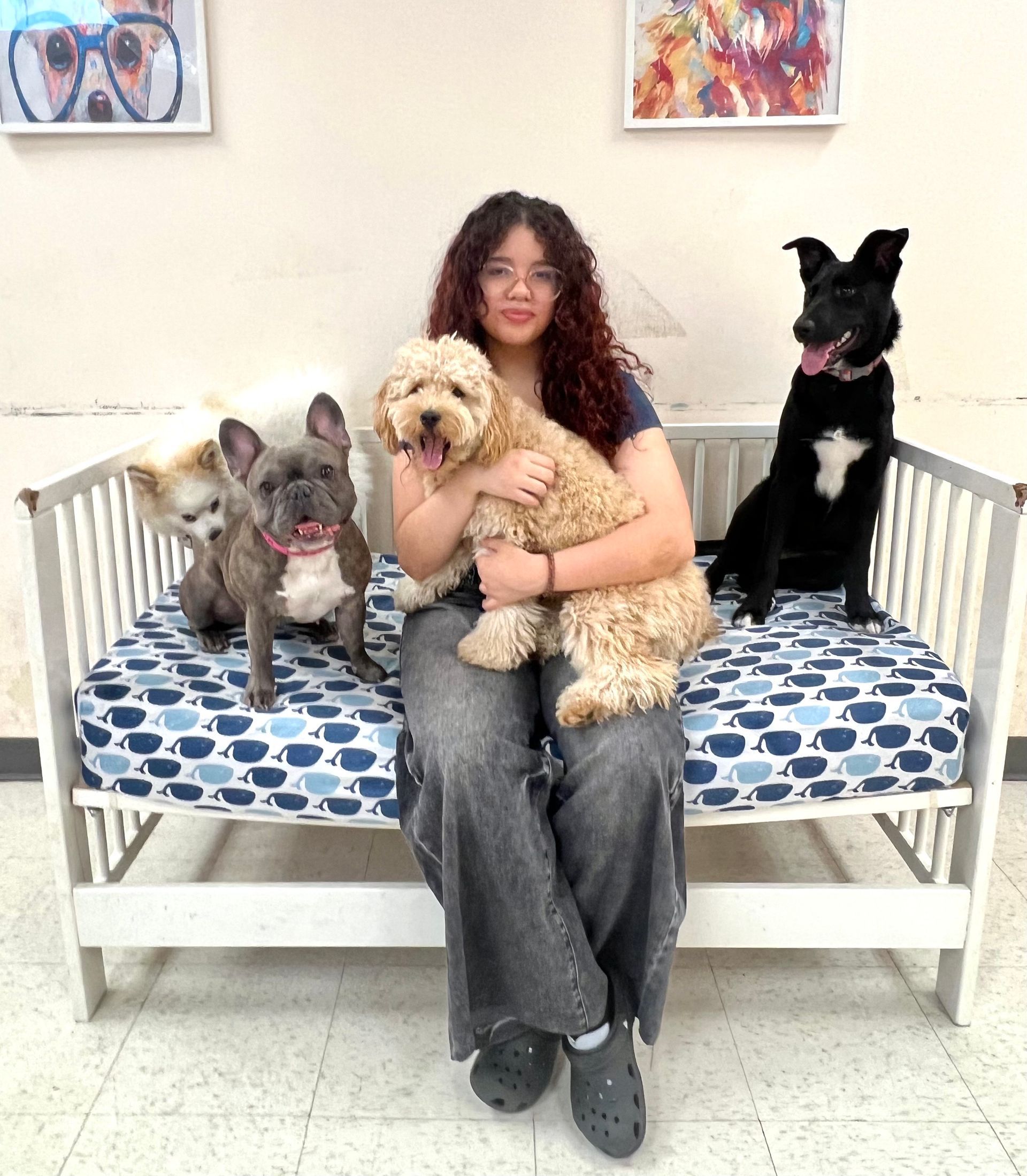 Woman in blue shirt seated in a teal chair, dog with brown spots sits beside her.