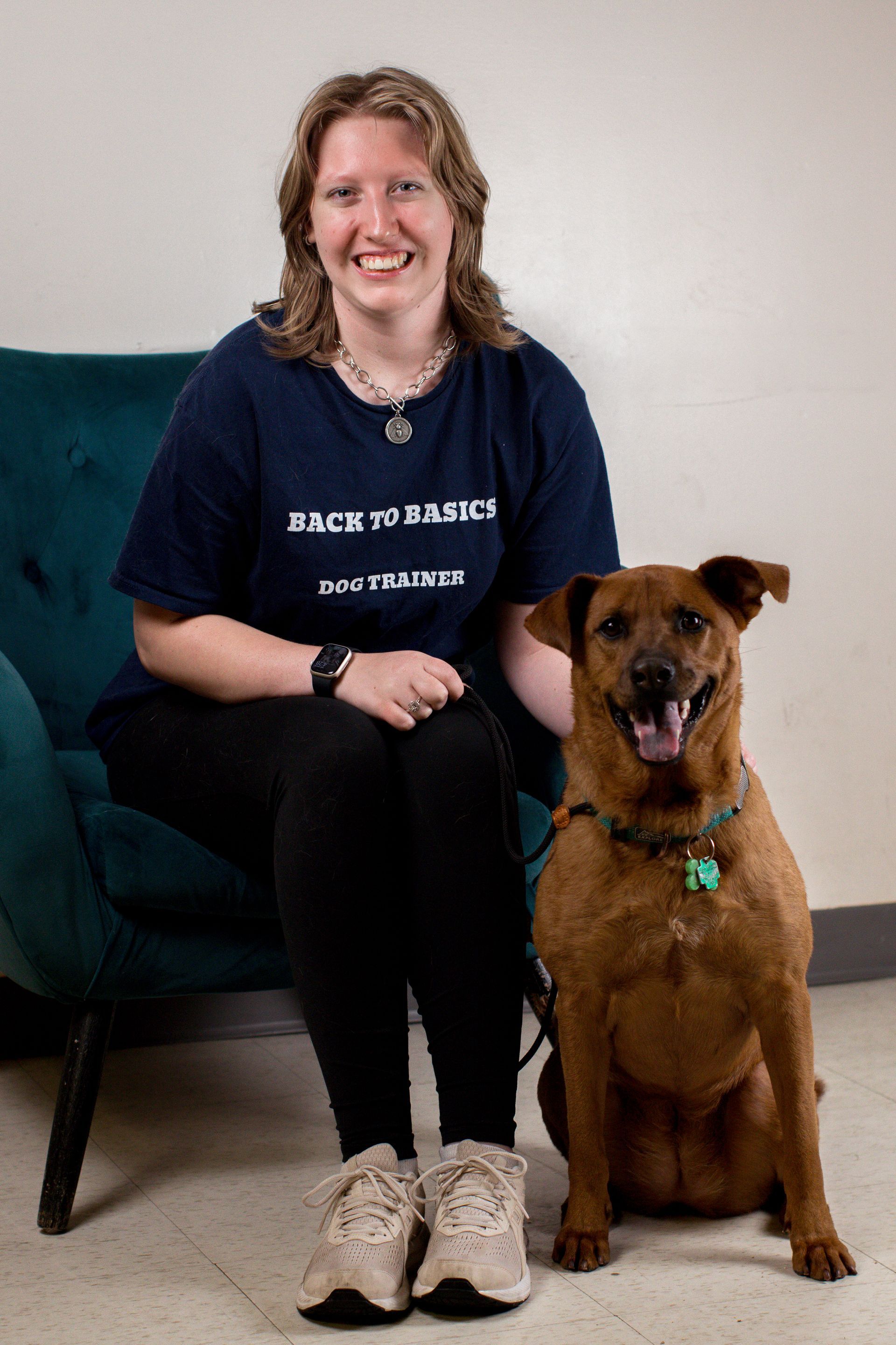 Woman in blue shirt sits with a brown dog on a green chair. Both are smiling at the camera.