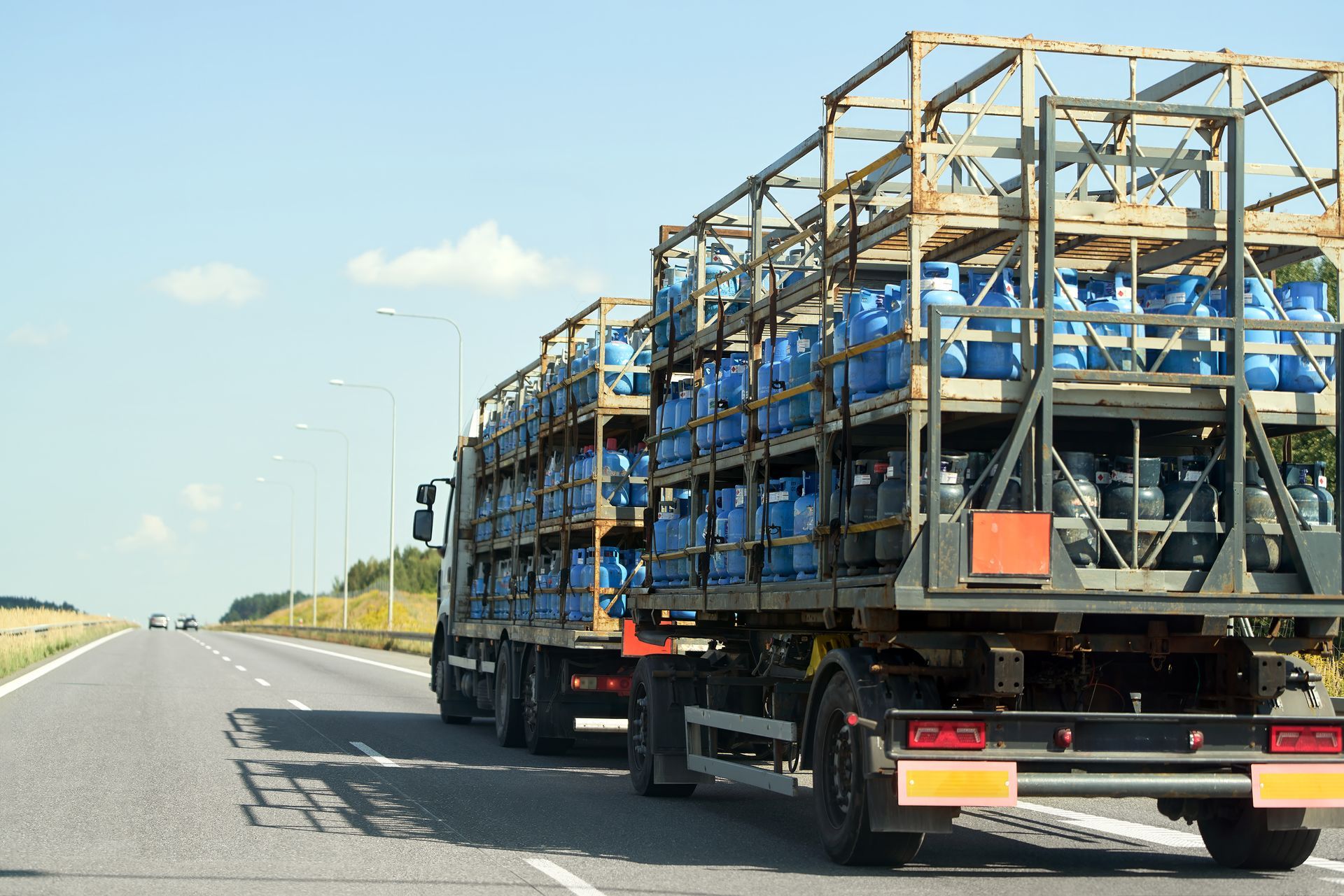 Car carrier truck hauling blue cars on a highway under a clear sky