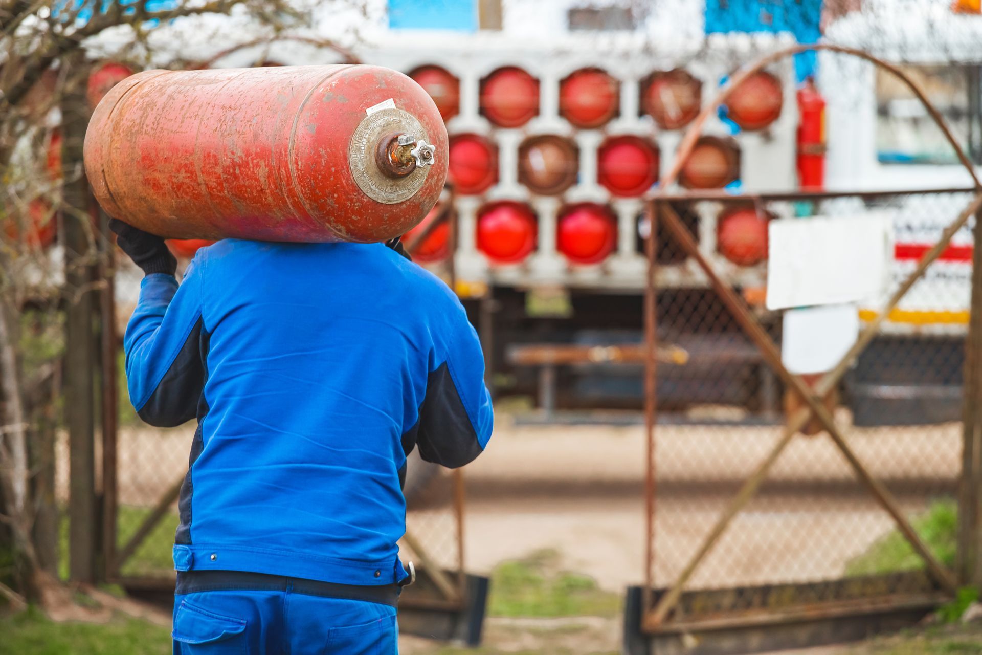 Worker carrying propane tank for residential delivery service. Worker carrying propane tank for residential delivery service.