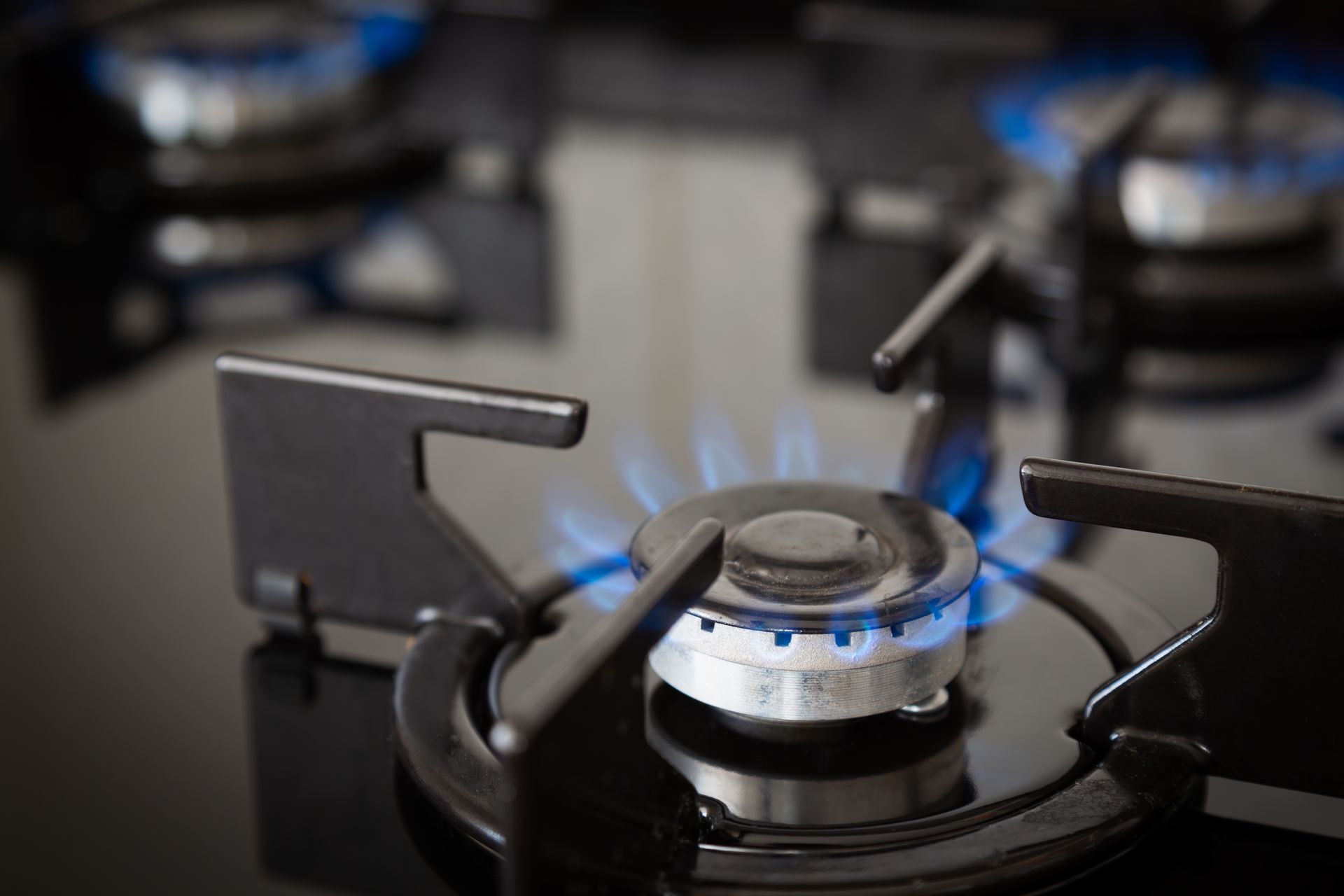 Propane delivery truck on its way to refill a property's propane tank. Blue gas flame on a black stovetop burner with pot supports.