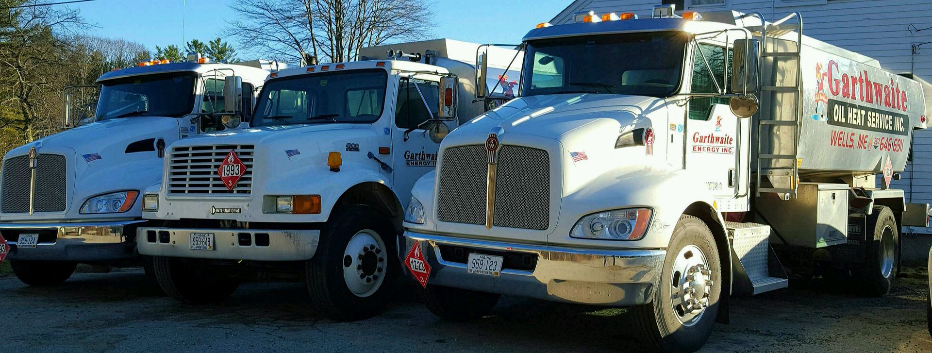 Red and silver tanker truck on a highway, transporting a flammable liquid, with a blue sky background.