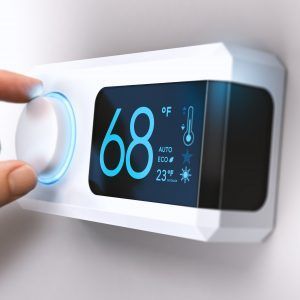 Hand turning a thermostat dial, digital display shows 68°F.