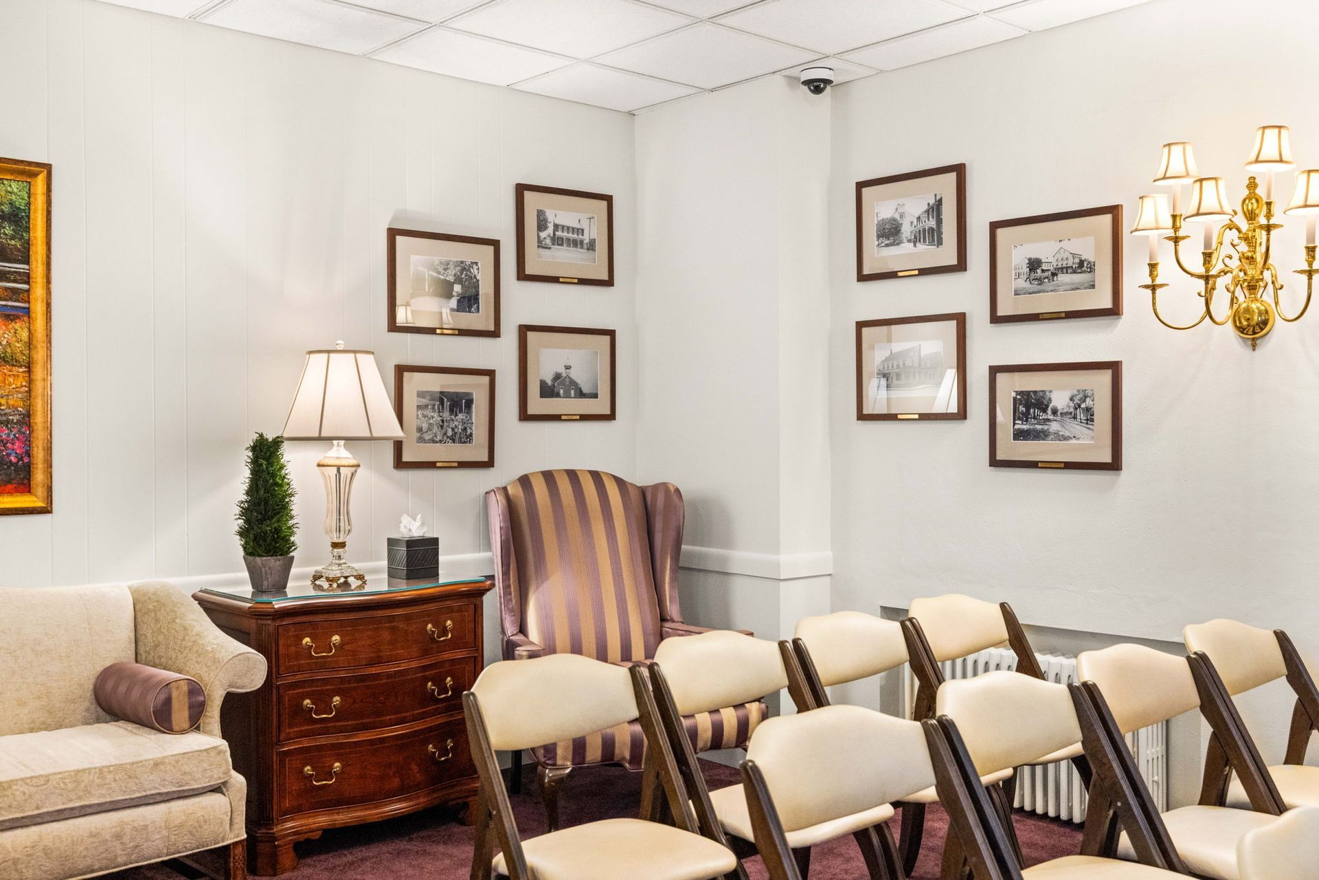 Empty room with rows of chairs, framed wall art, a lamp, and a chandelier