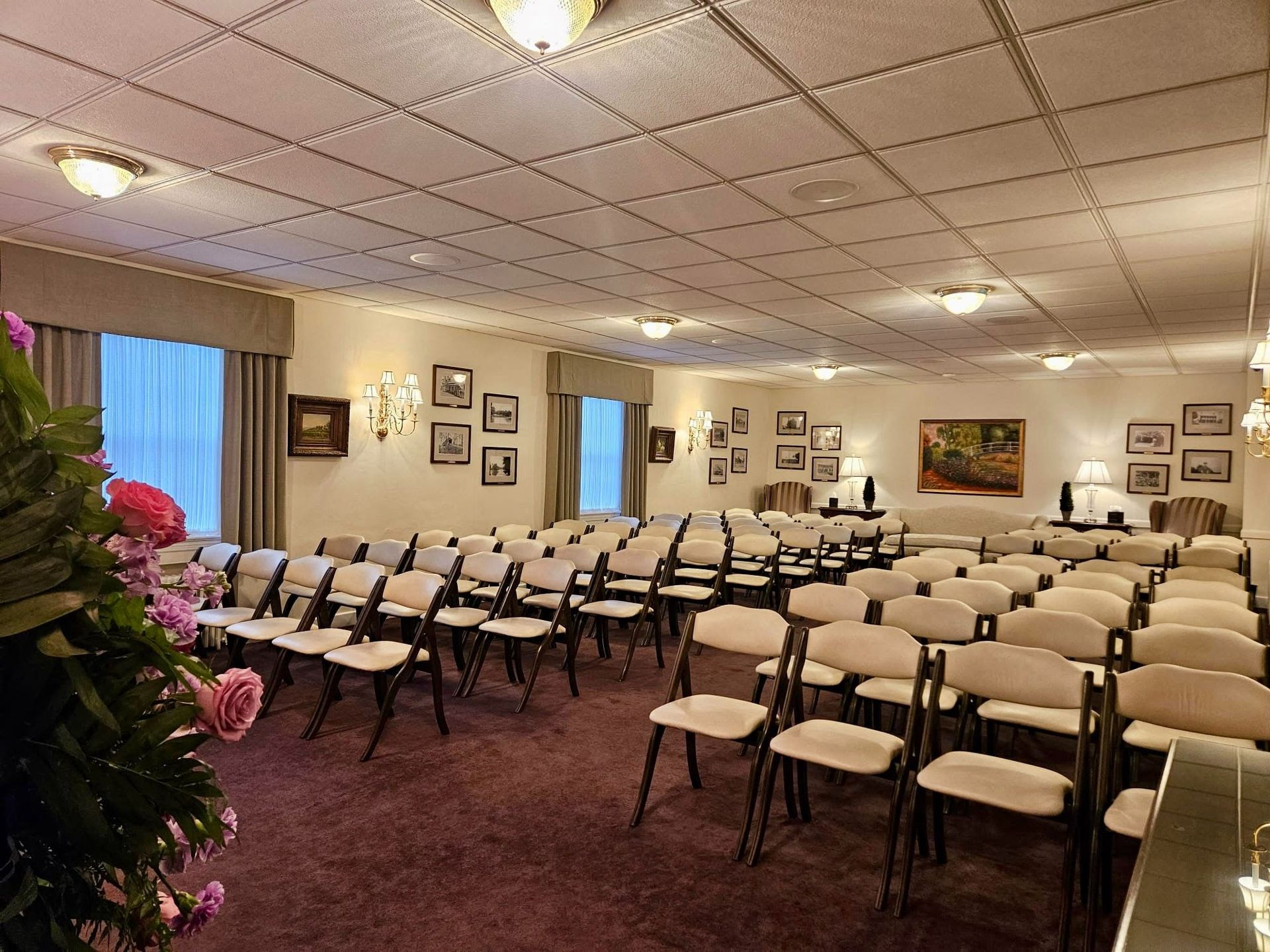 Rows of white chairs set up in a decorated hall with a Christmas tree and wall art.