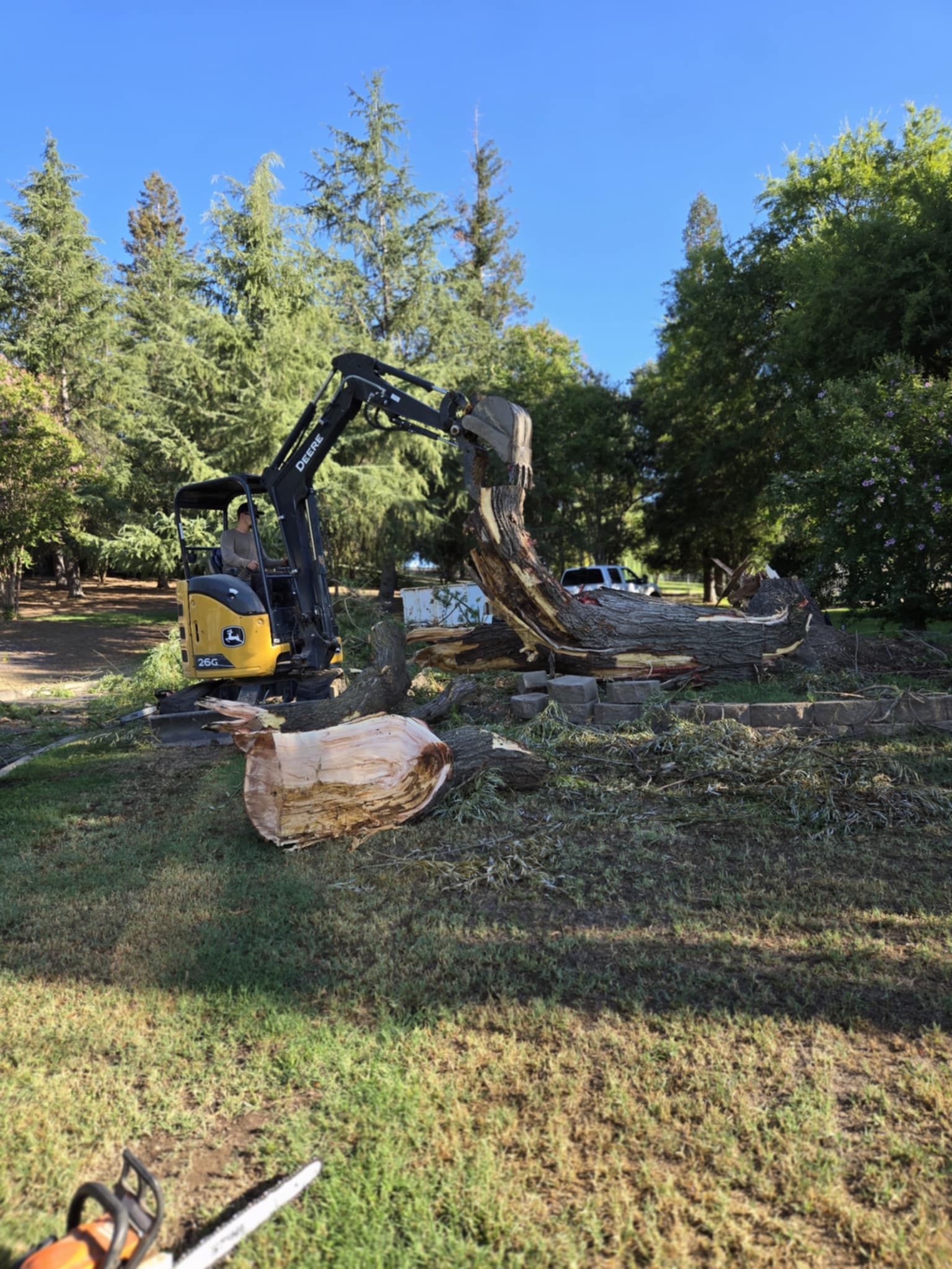 Construction worker in white hard hat watching an excavator grading a dirt site