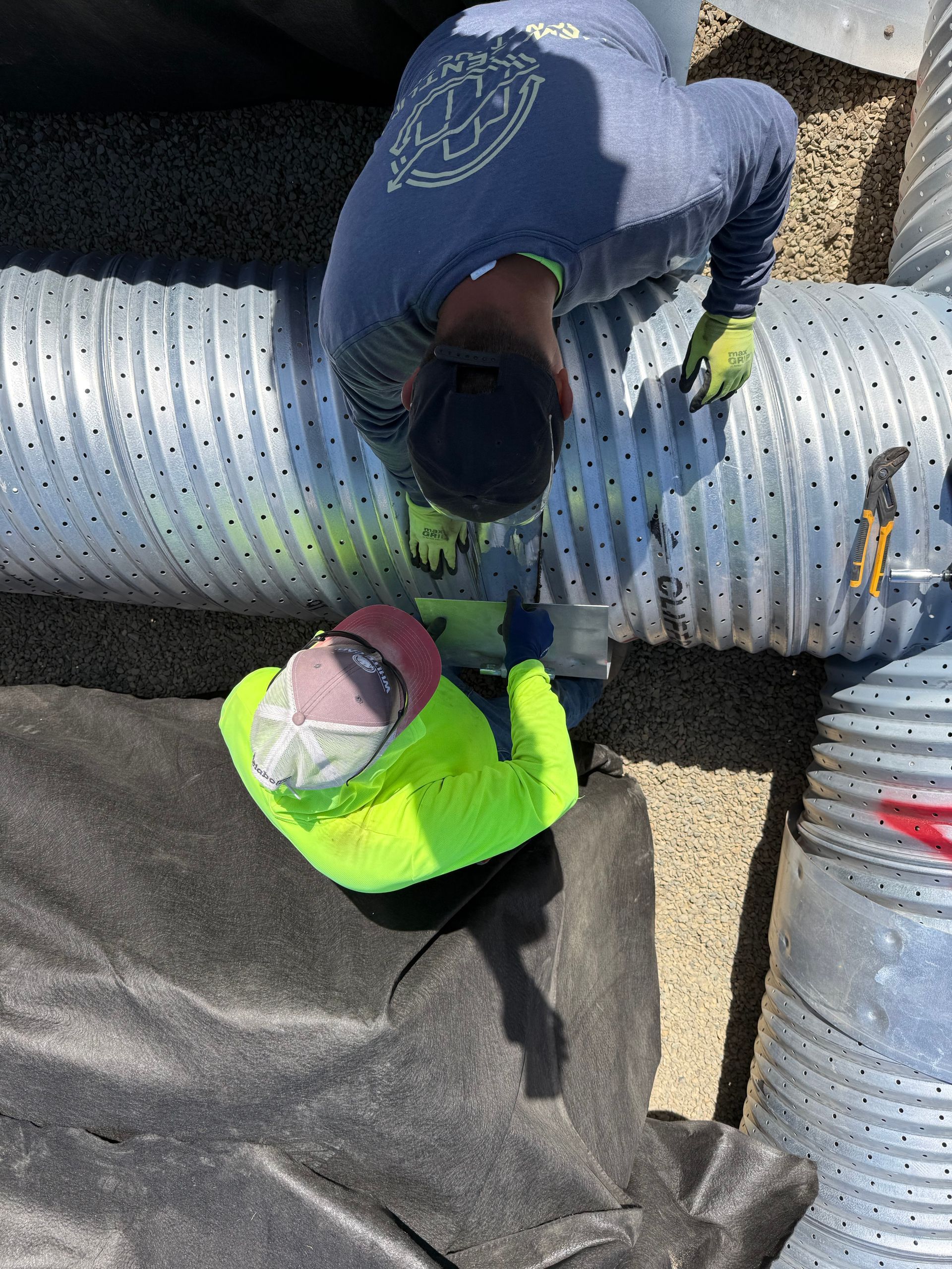 Orange and gray PVC pipes joined in a dirt trench underground