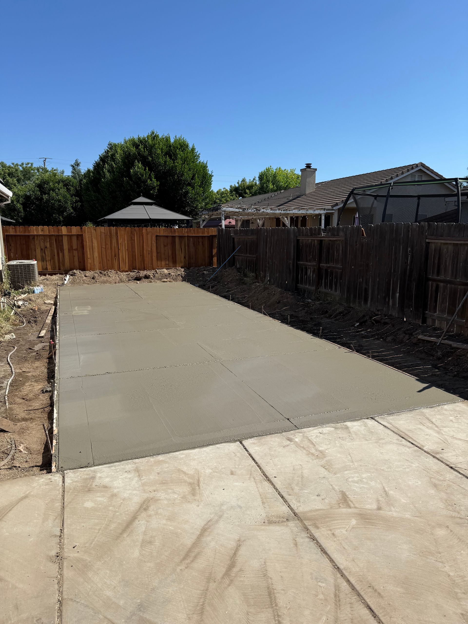 Worker laying gray paving stones beside red bricks during outdoor patio construction