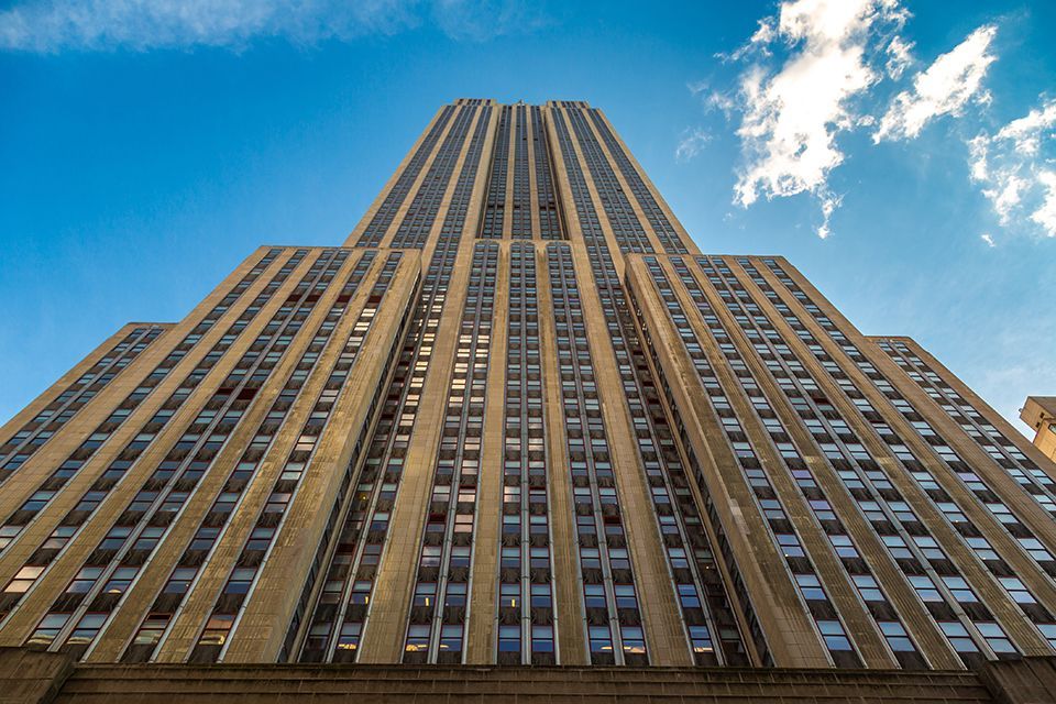 looking up at the Empire State building with a blue sky in the background