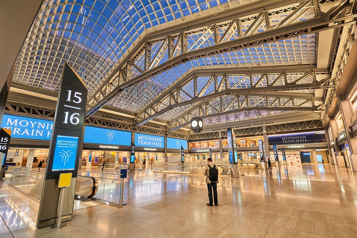 a man is standing in the middle of Moynihan station