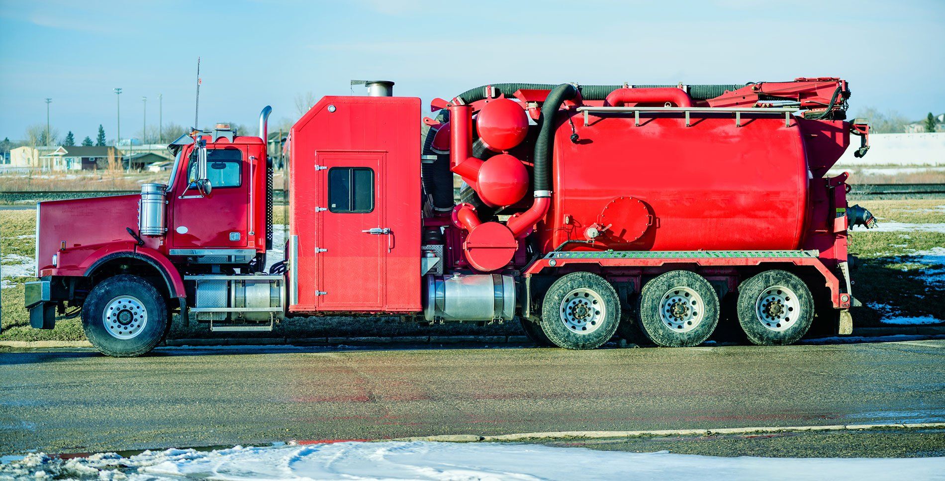 Red tanker truck parked on a wet roadway, carrying red equipment and cylinders.