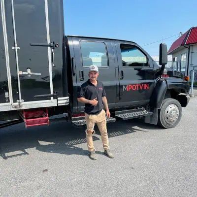 Un homme se tient devant un camion noir.