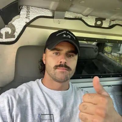 Un homme avec une moustache lève le pouce dans une camionnette.
