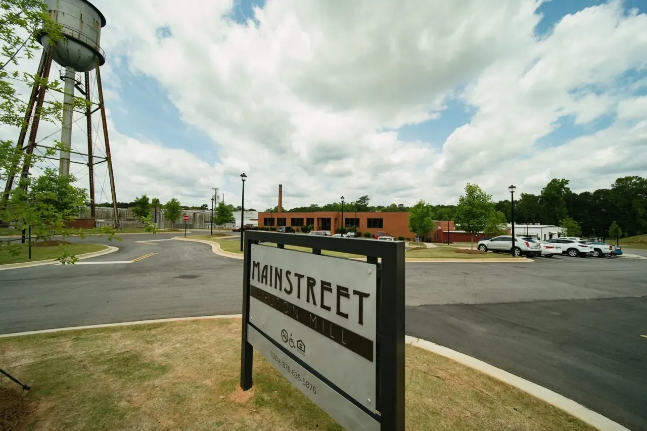 Exterior view of the MainStreet apartment community sign with parking lot and brick building.