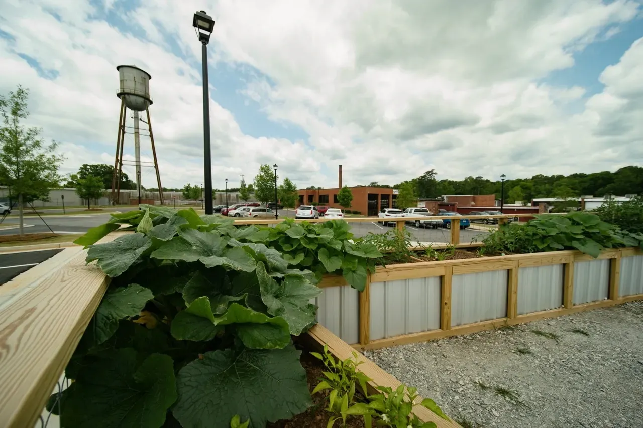 Exterior community area with wooden railing, planters, and a parking lot under a cloudy sky.