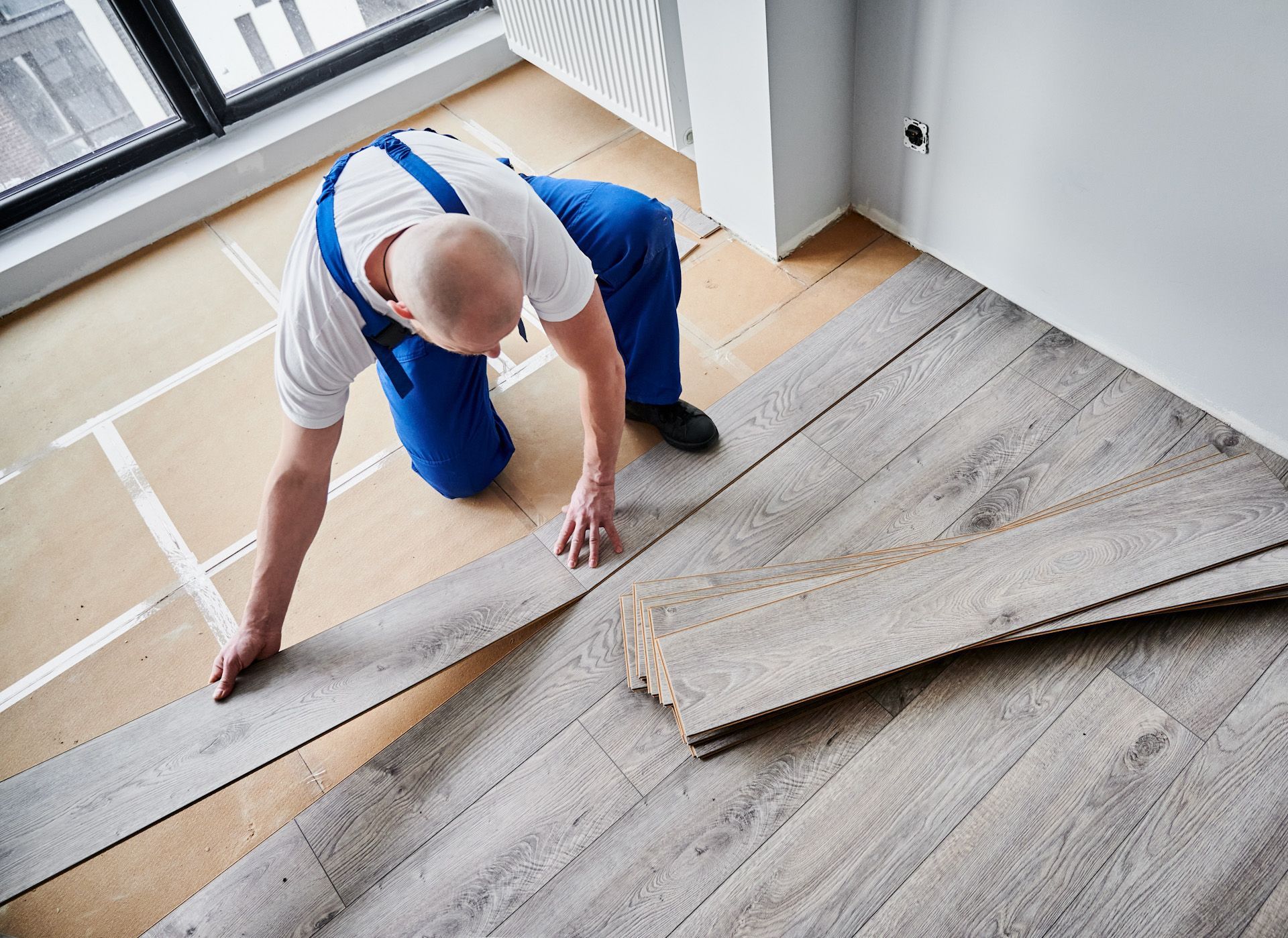 A man is installing a wooden floor in a room.