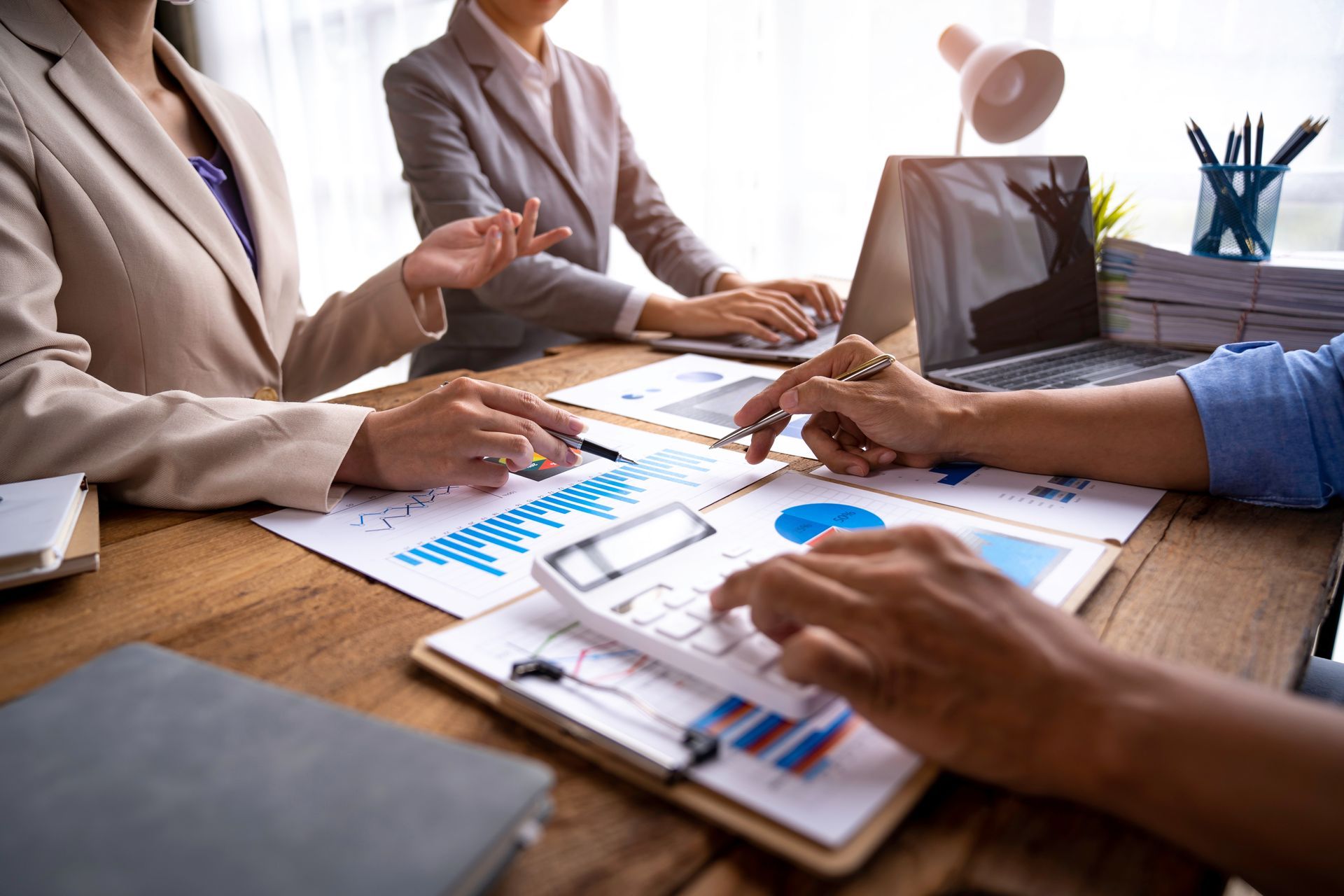 Business team reviewing charts and documents around a meeting table with a laptop and notebooks