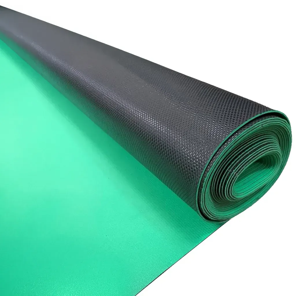 Tapete negro texturizado enrollado sobre una superficie verde, parcialmente desenrollado para mostrar la parte verde