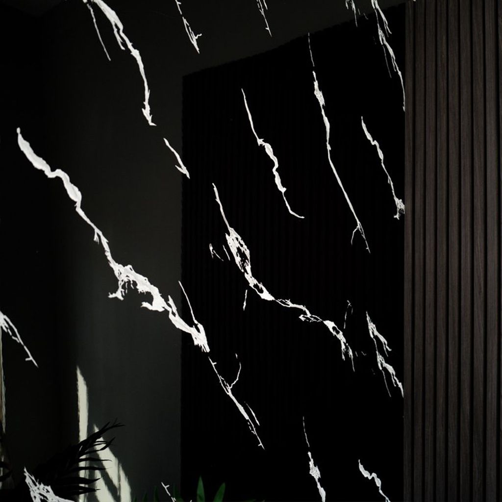 Mesita redonda de madera con elementos decorativos en una habitación moderna: vela, difusor, pared de mármol