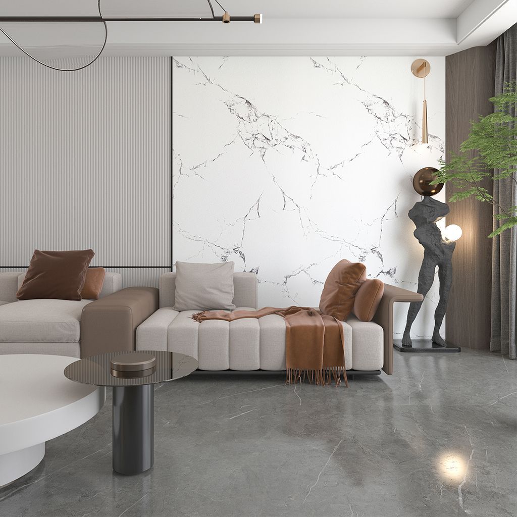 Sala de estar moderna con sofá seccional beige, pared decorativa de mármol, suelo gris y decoración escultural.