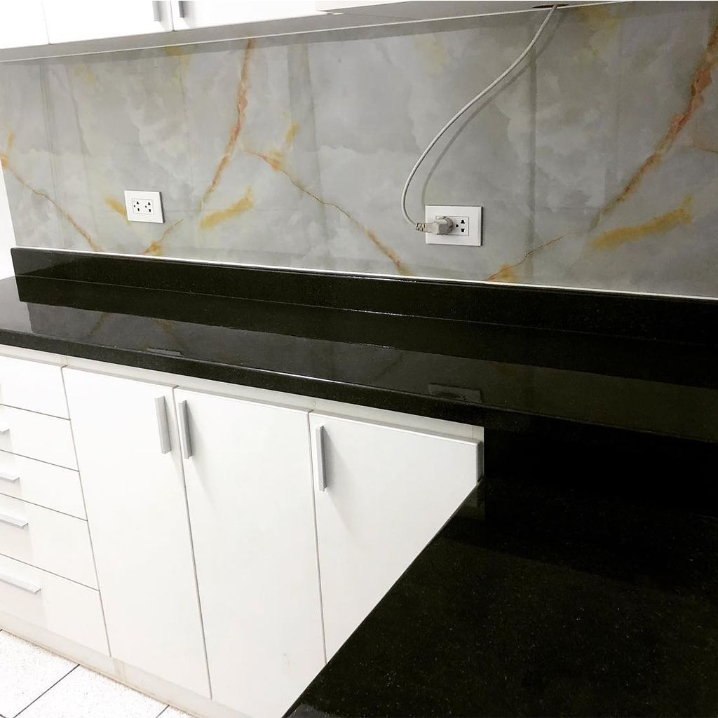 Pared interior moderna con panel de mármol, vetas doradas y listones de madera verticales junto a un aire acondicionado.