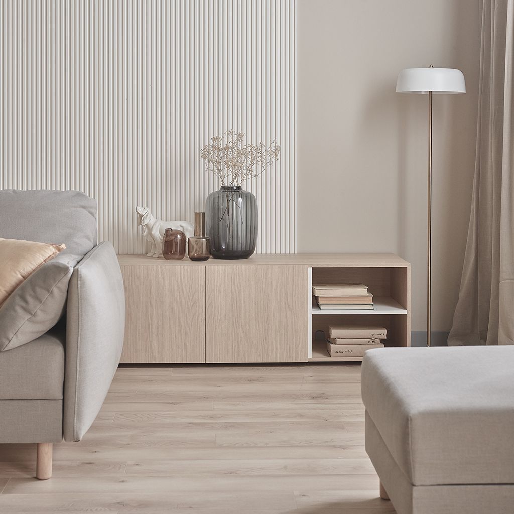 Sala de estar minimalista en tonos beige con sofá, aparador, lámpara de pie y jarrones decorativos.