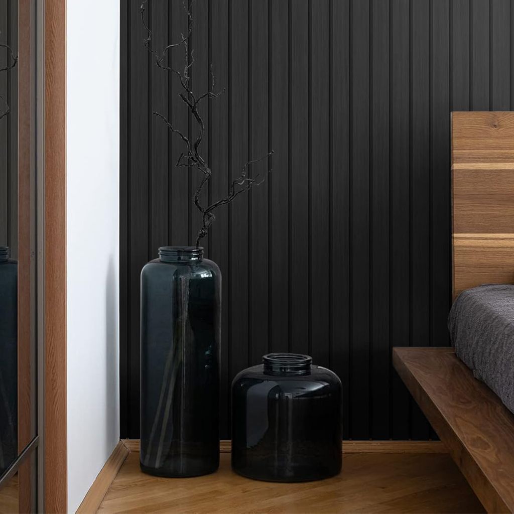 Rincón de dormitorio moderno con jarrones negros, ramas altas, pared revestida de paneles negros
