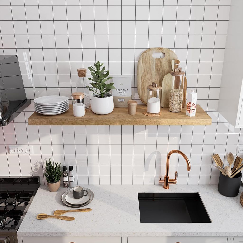 Encimera de cocina moderna con fregadero negro, grifo de cobre, estante abierto y vajilla y decoración ordenadas.