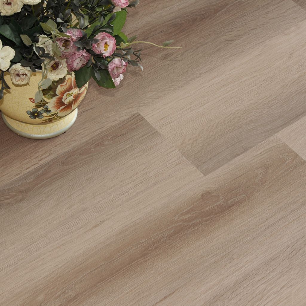 Dormitorio minimalista en tonos beige con tocador, espejo redondo, cama y sillón mullido sobre suelo de madera clara.