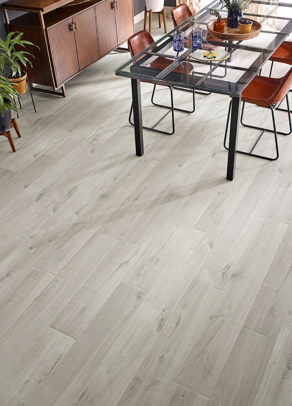 Comedor moderno con mesa de madera, sillas, plantas y suelo gris claro.