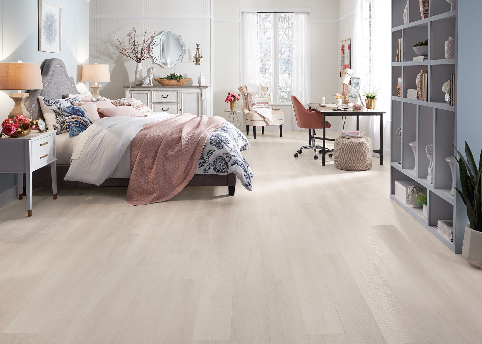 Habitación luminosa con cama, escritorio, estanterías y suelo de madera clara.