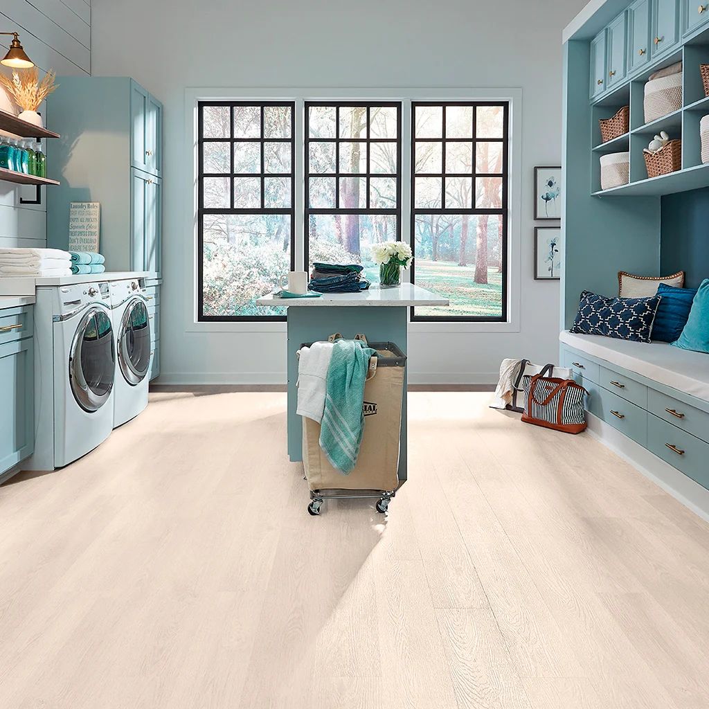 Habitación luminosa con cama, escritorio, estanterías y suelo de madera clara.