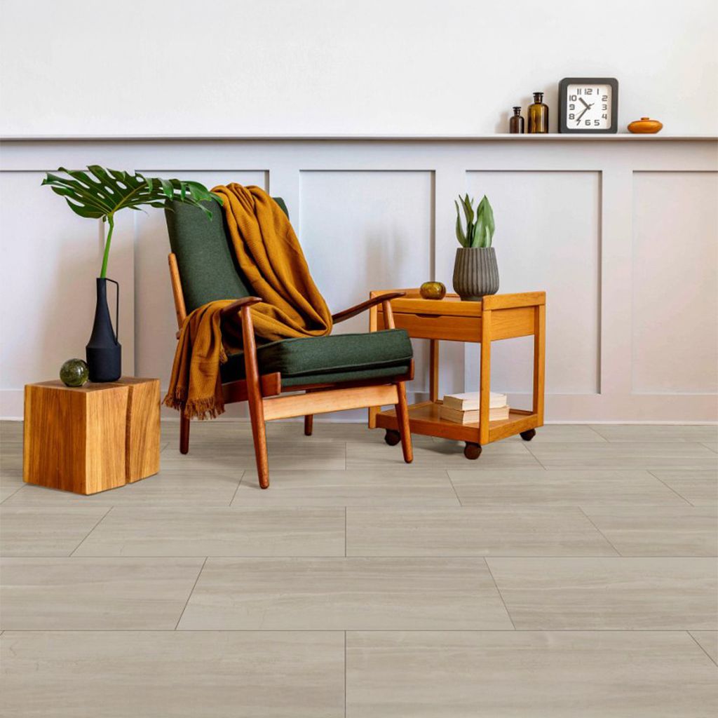 Acogedor rincón de salón con sillón verde, manta color mostaza, mesitas auxiliares de madera, planta