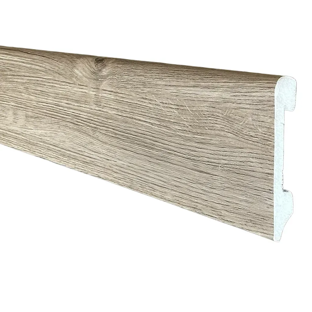 Moldura de zócalo de madera color beige con perfil de borde blanco, mostrada sobre un fondo blanco.