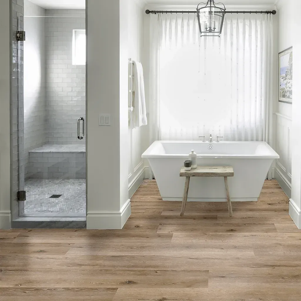 Luminoso salón moderno con sofá gris, mesa de centro, alfombra, suelo de madera y una gran puerta corredera de cristal.