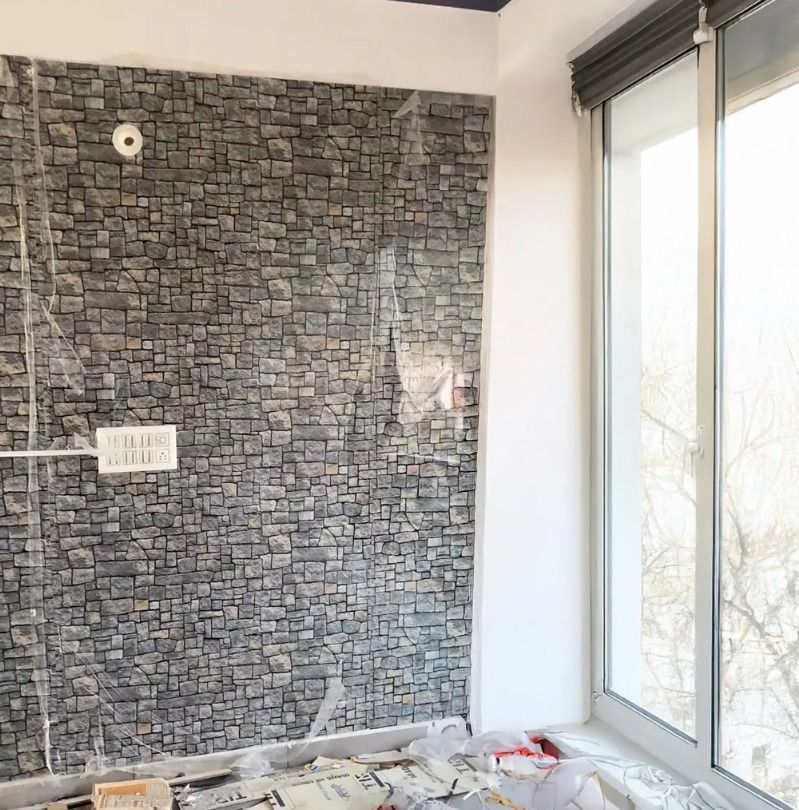Silla de mimbre con cojín a rayas contra una pared de piedra, flanqueada por jarrones blancos y plantas en macetas.