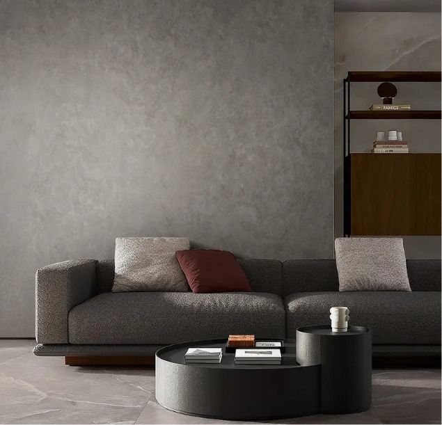 Sala de estar moderna en color gris con sofá seccional oscuro, mesa de centro redonda negra y estanterías minimalistas.
