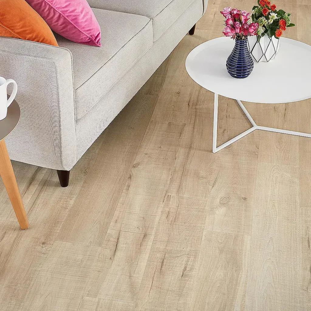Sala de estar moderna con sofá beige, mesa de centro blanca y flores sobre suelo de madera clara.