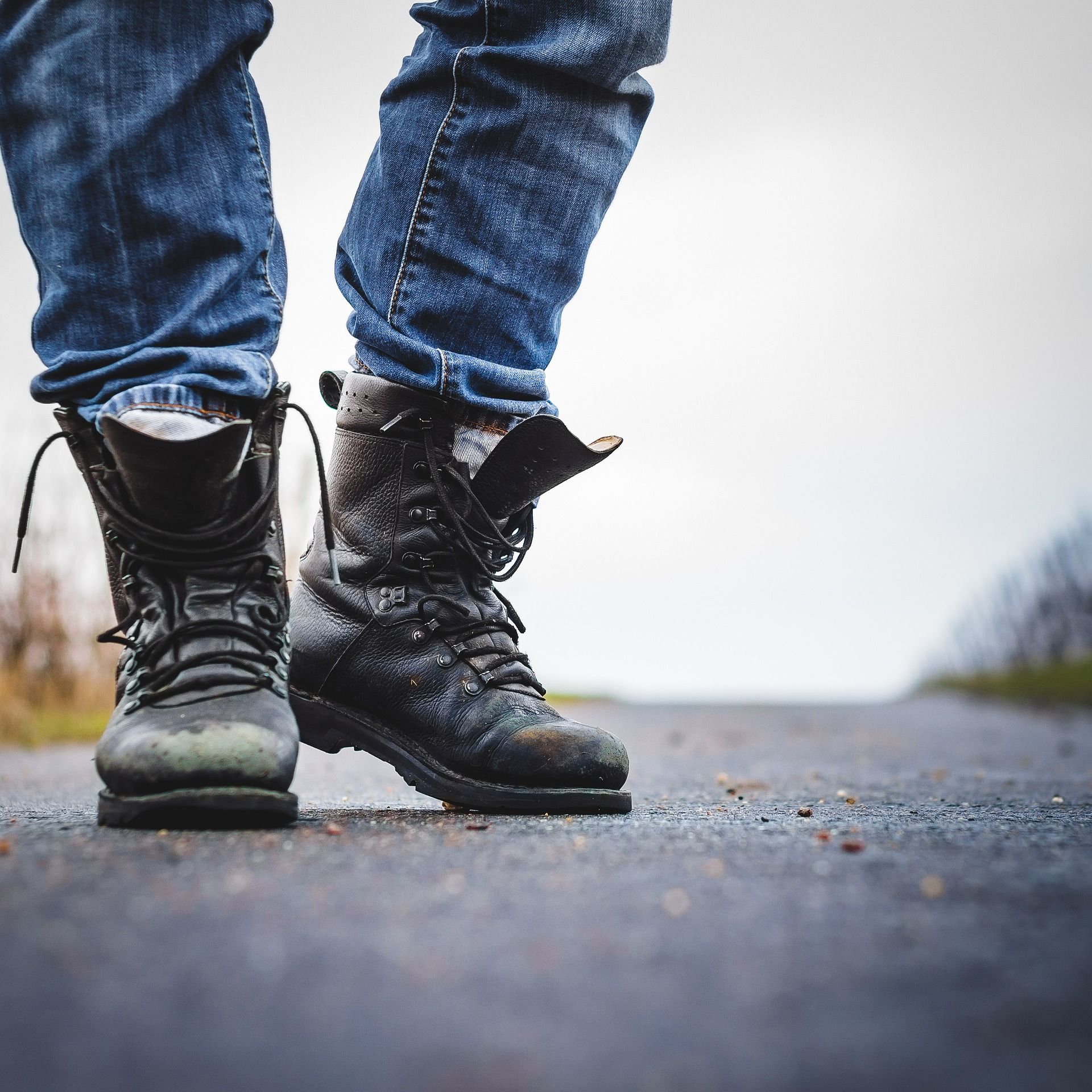 A person wearing a pair of black boots standing on a road