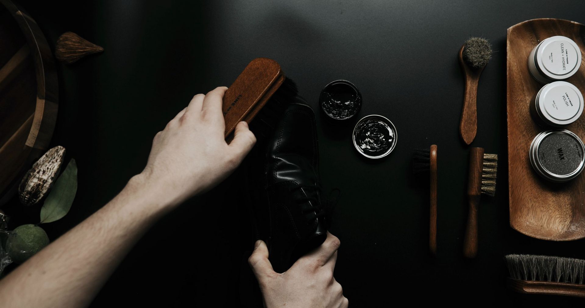 A person is cleaning a shoe with a brush on a table.