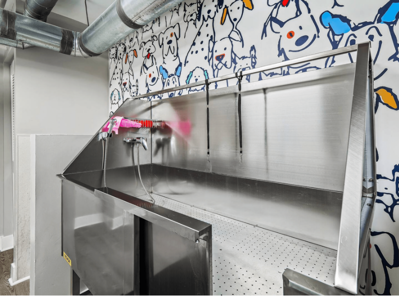 A stainless steel sink in a room with a mural of dogs on the wall.